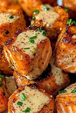 Bang Bang Salmon Bites served on a plate, garnished with sauce and herbs.