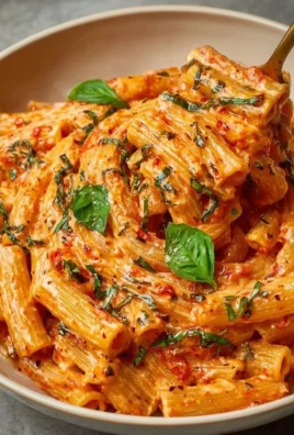 Creamy tomato garlic pasta garnished with fresh herbs and parmesan cheese