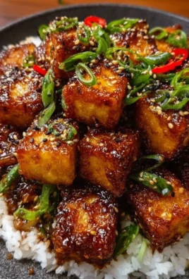 Crispy honey garlic tofu garnished with green onions and sesame seeds.