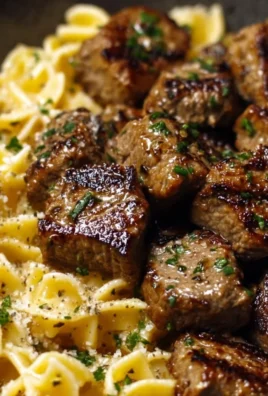 Garlic butter steak bites served with creamy parmesan pasta on a plate