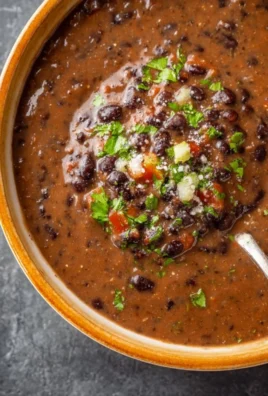 Bowl of hearty black bean soup garnished with cilantro and lime.