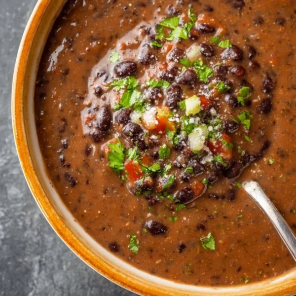 Bowl of hearty black bean soup garnished with cilantro and lime.