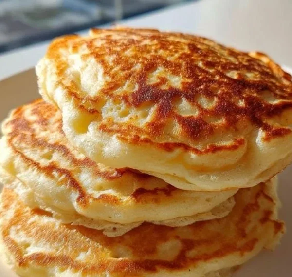 Fluffy high-protein Greek yogurt pancakes stacked on a plate with syrup