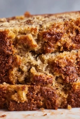 Sliced banana bread on a wooden cutting board with bananas and nuts