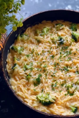 Creamy broccoli cheddar orzo dish topped with fresh herbs
