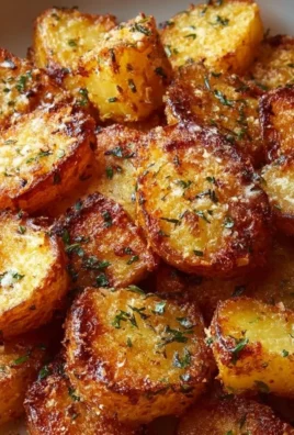 Plate of crispy Parmesan potatoes garnished with herbs