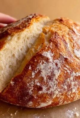 Freshly baked no knead bread loaf resting on a wooden cutting board