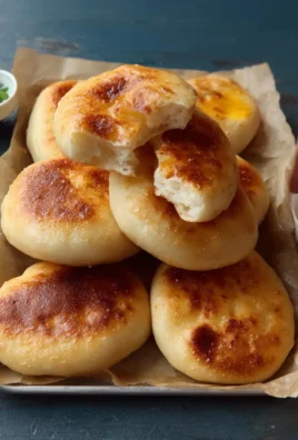 Soft fried buns on a wooden plate garnished with herbs