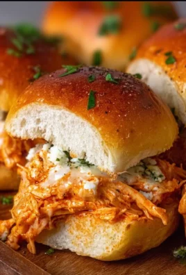Spicy buffalo chicken sliders served on a platter with dipping sauce.