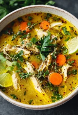 Bowl of anti-inflammatory turmeric chicken soup garnished with fresh herbs