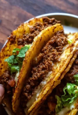 Plate of crispy ground beef tacos topped with fresh vegetables