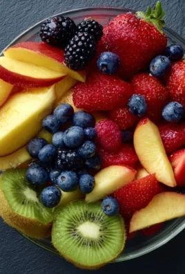 Colorful bowl of fresh fruit salad with assorted fruits like berries, melon, and kiwi.