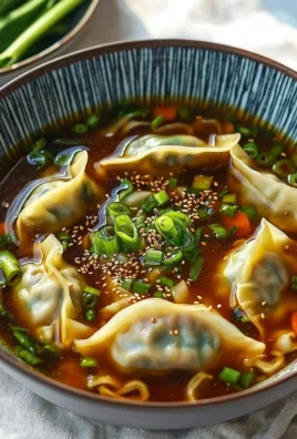 A bowl of Gyoza Soup with dumplings and green onions on top, served in a rustic bowl.