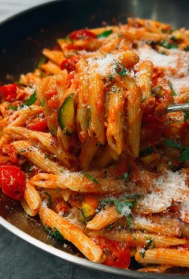 Bowl of roasted veggie pasta topped with garlic tomato sauce