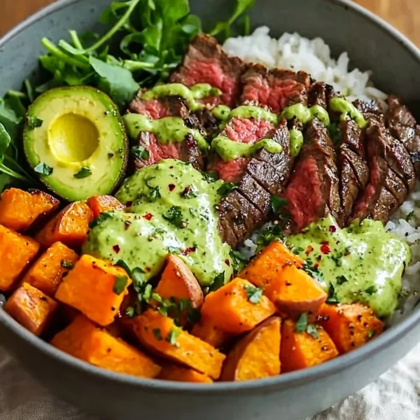 Steak and sweet potato bowls with avocado-cilantro drizzle on a plate